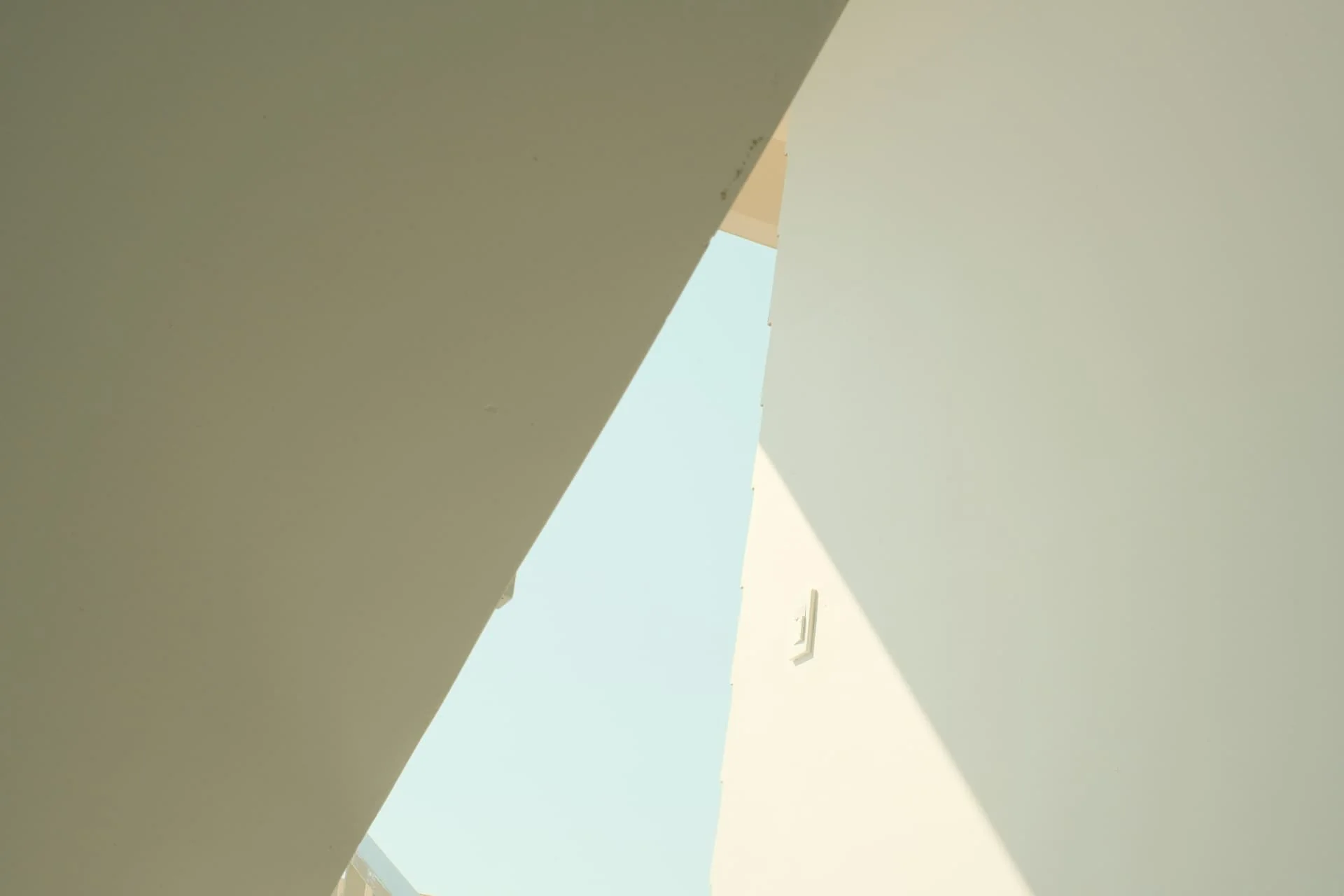 Sunlit pale walls meeting at sharp angles against a blue sky